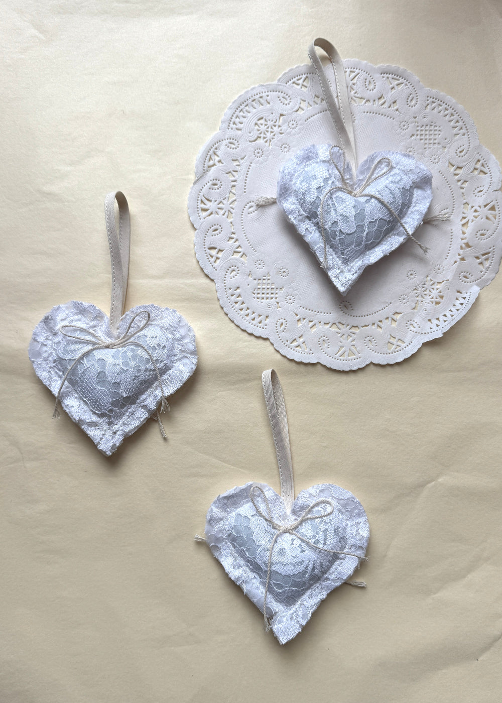 White lace Christmas heart in textile by AMANDA BUGGE studio with a ivory bow on