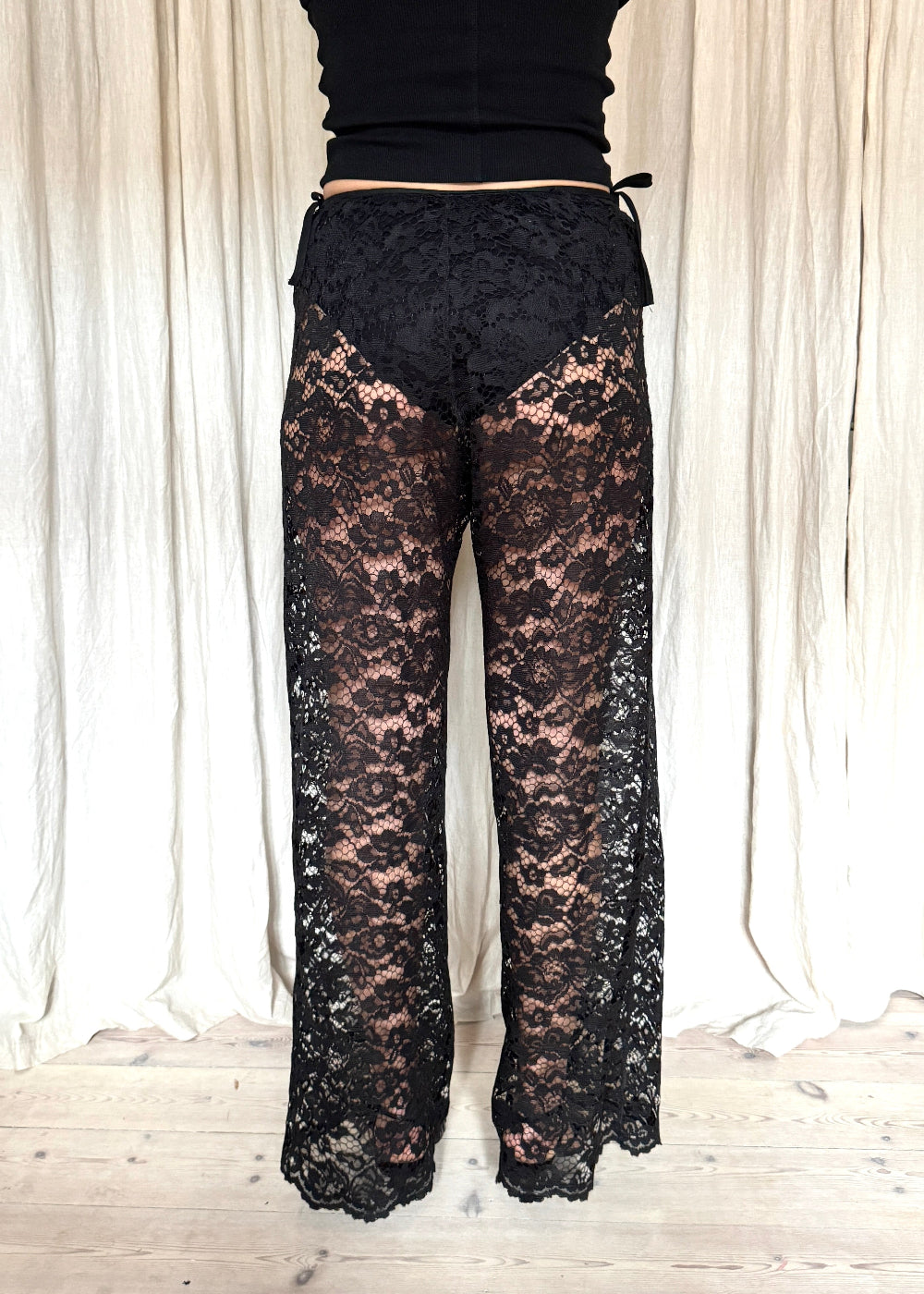 Model wearing black Nora Lace Pants in sheer lace with a relaxed fit and drawstring waist
