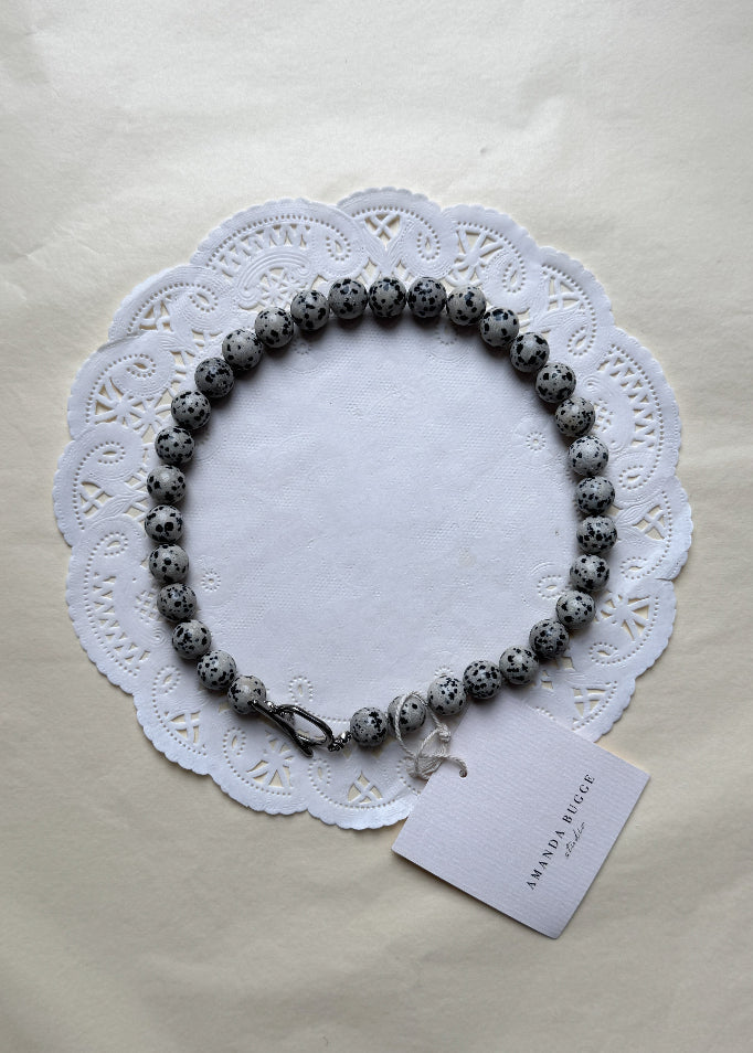 Bold Dalmatian necklace by AMANDA BUGGE studio – minimalist damatian beaded choker necklace with silver toggle clasp, styled on white lace-edged fabric