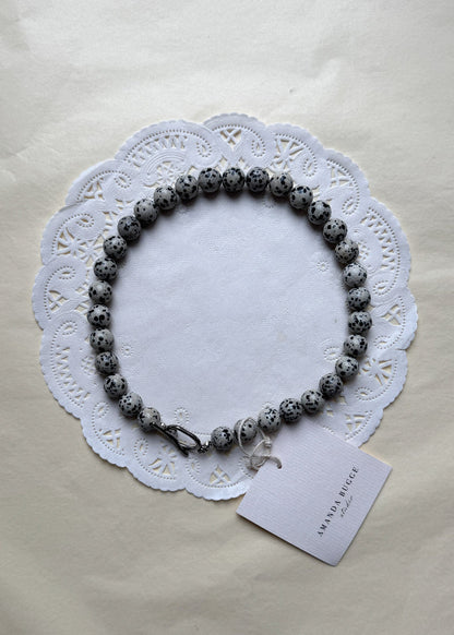 Bold Dalmatian necklace by AMANDA BUGGE studio – minimalist damatian beaded choker necklace with silver toggle clasp, styled on white lace-edged fabric
