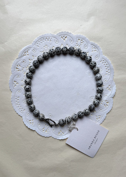Bold Dalmatian necklace by AMANDA BUGGE studio – minimalist damatian beaded choker necklace with silver toggle clasp, styled on white lace-edged fabric