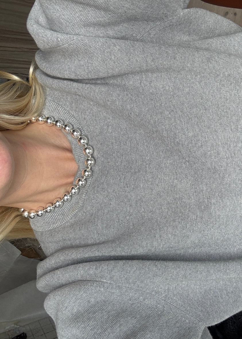 Bold silver necklace by AMANDA BUGGE studio – minimalist silver beaded choker necklace with silver toggle clasp, styled on white lace-edged lace fabric on