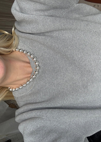 Bold silver necklace by AMANDA BUGGE studio – minimalist silver beaded choker necklace with silver toggle clasp, styled on white lace-edged lace fabric on