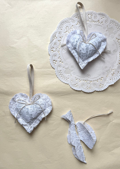 White lace Christmas heart in textile by AMANDA BUGGE studio with a ivory bow on and bird in white lace
