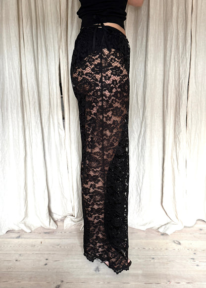 Model wearing black Nora Lace Pants in sheer lace with a relaxed fit and drawstring waist from side