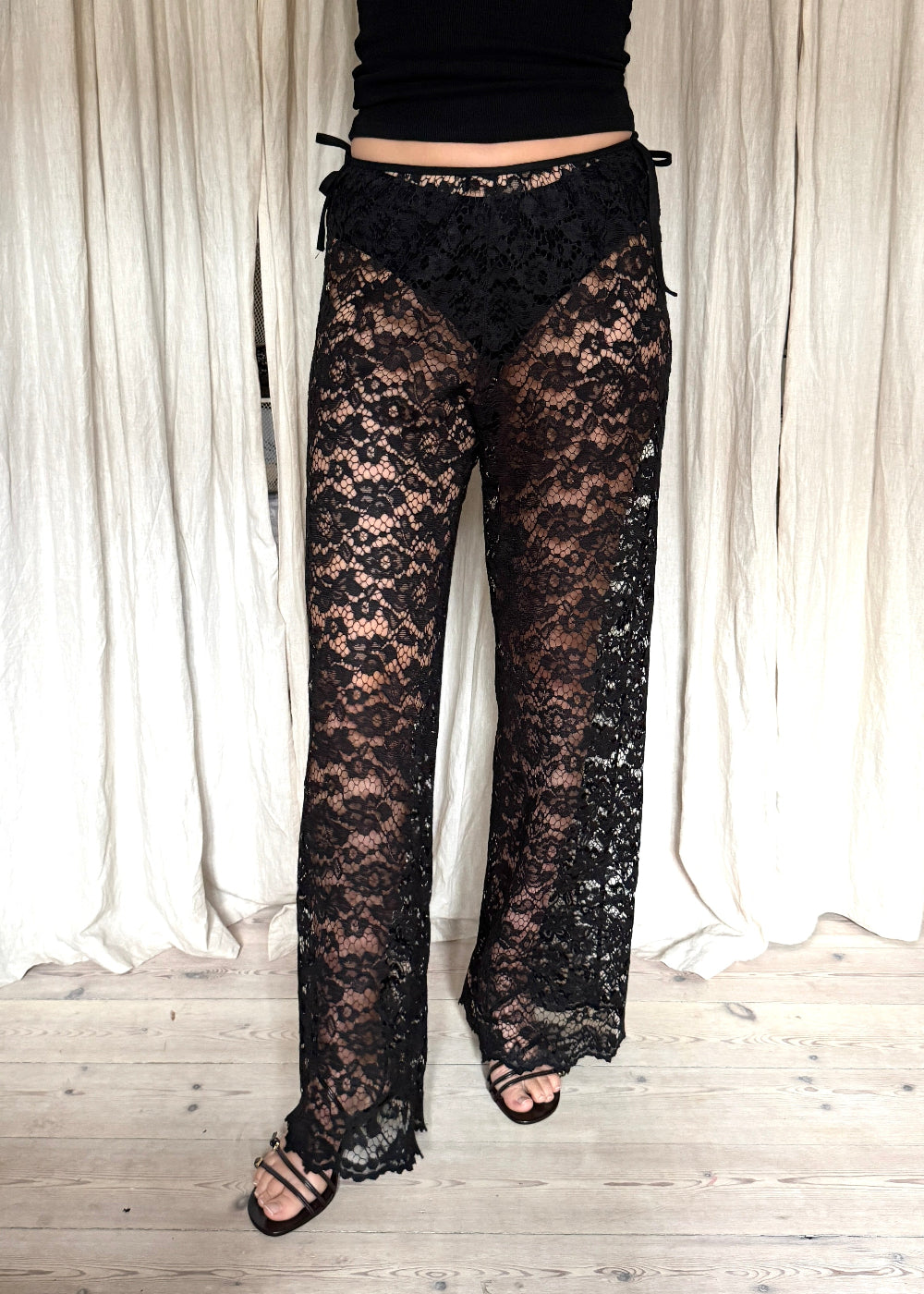 Model wearing black Nora Lace Pants in sheer lace with a relaxed fit and drawstring waist